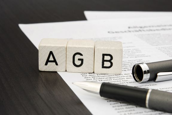 Würfel mit den Buchstaben A G und B und Papier und Stift auf Tisch
